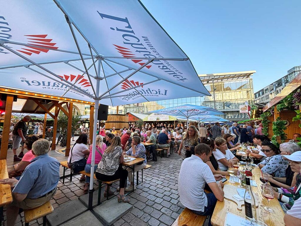 People Drinking and Laughing at Tables at the Chemnitz Wine Festival in Germany